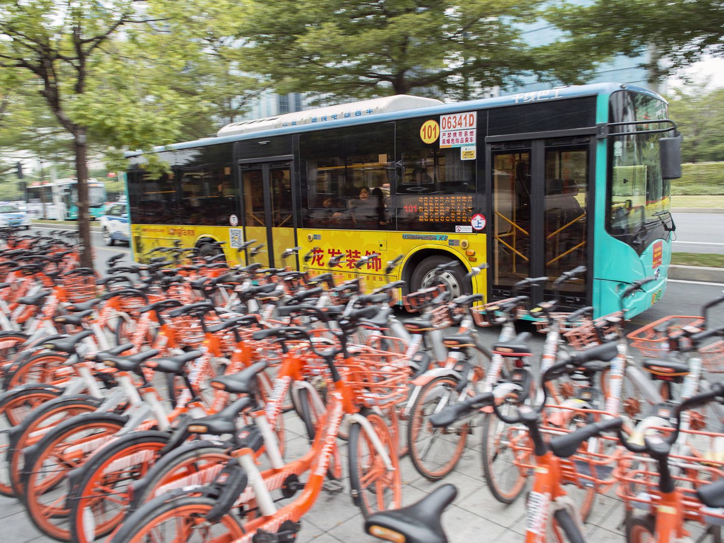 Un autobús eléctrico pasa frente a un aparcamiento de bicicletas compartidas, otro avance en la movilidad de Shenzhen. (Z. Aldama)