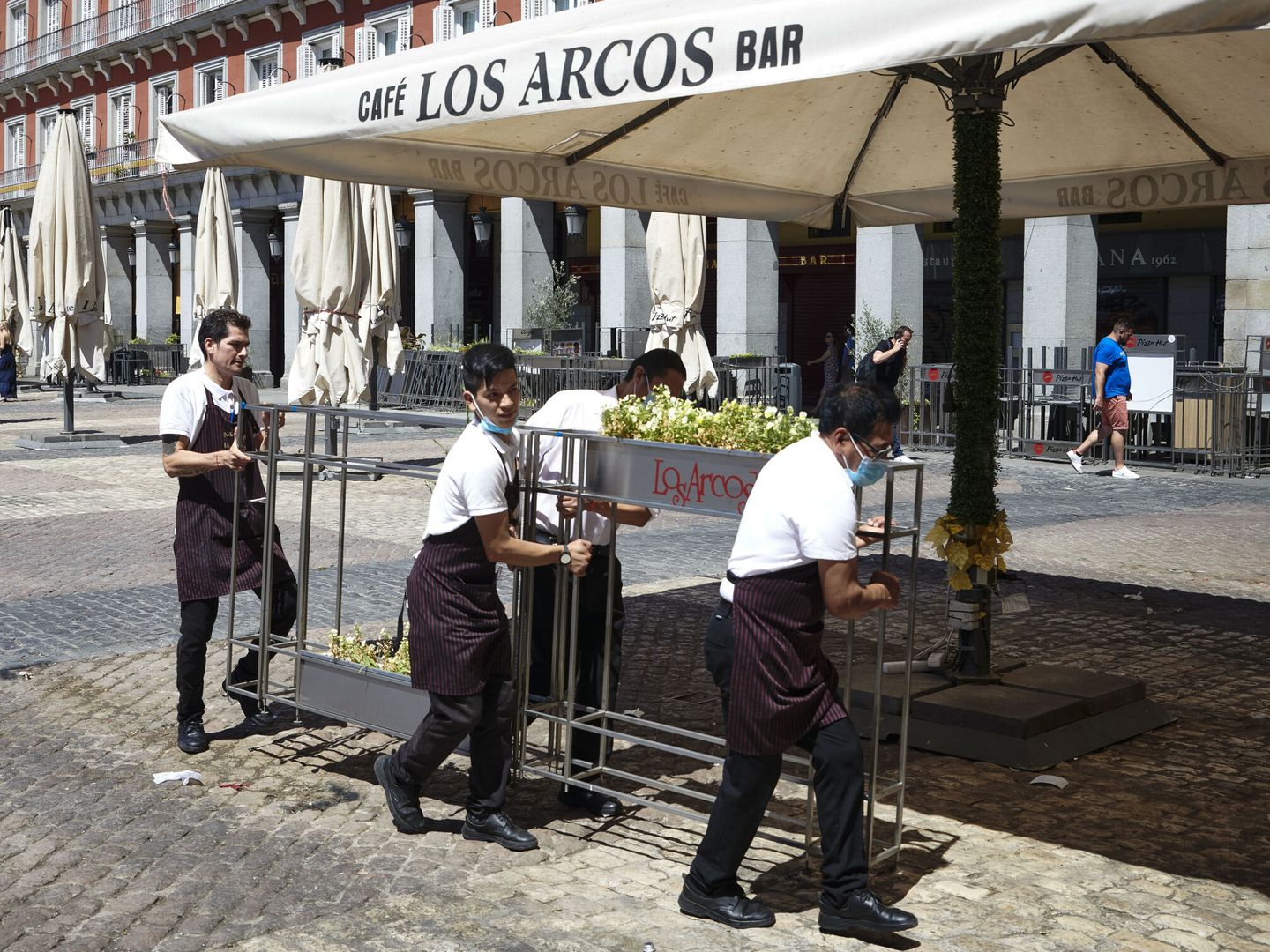 Hosteleros de la plaza Mayor, que esta tarde han tenido que retirar sus terrazas por 'motivos de seguridad'. (EFE/Luca Piergiovanni)
