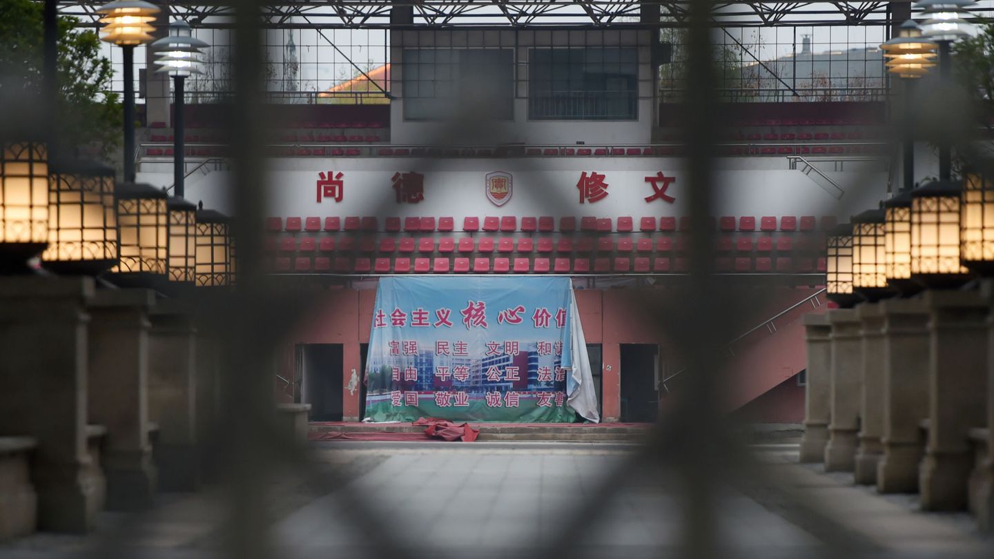 Una pancarta que muestra los valores socialistas centrales de China se ve a través de la entrada de una escuela secundaria cerrada en Wuhan (EFE)