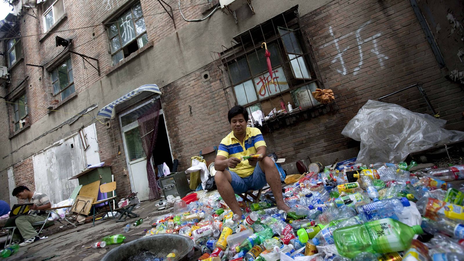 Foto: Un recolector de basura separa materiales reciclables de una pila de desechos frente a un edificio antes de su demolición, en Pekín. (EFE)