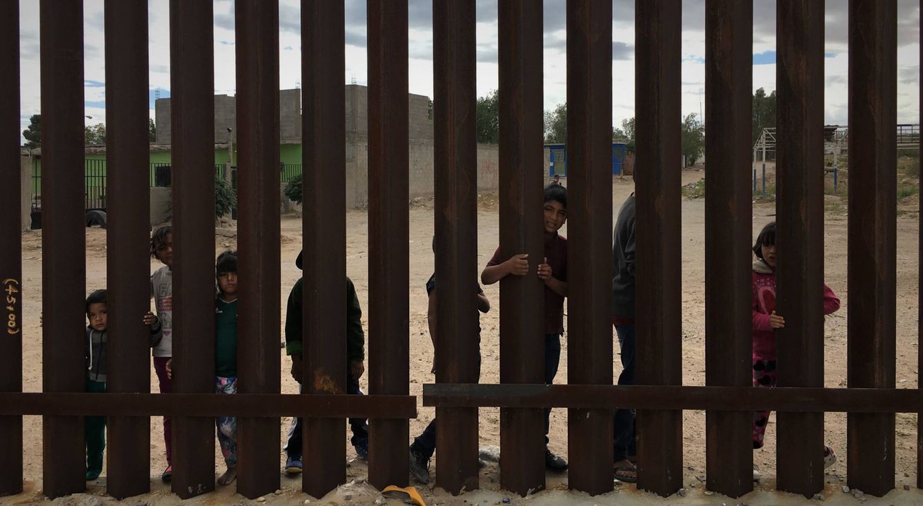 Un grupo de niños mexicanos se agarra a los barrotes de la valla fronteriza. (C. Pérez Cruz)