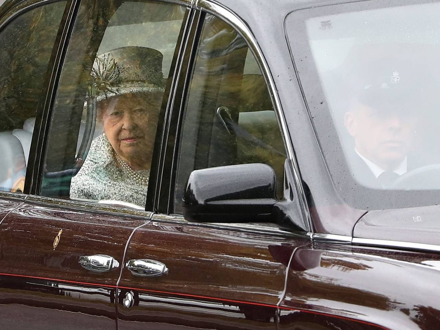 La reina Isabel II con su look aperlado y su gesto pensativo. (Cordon Press)