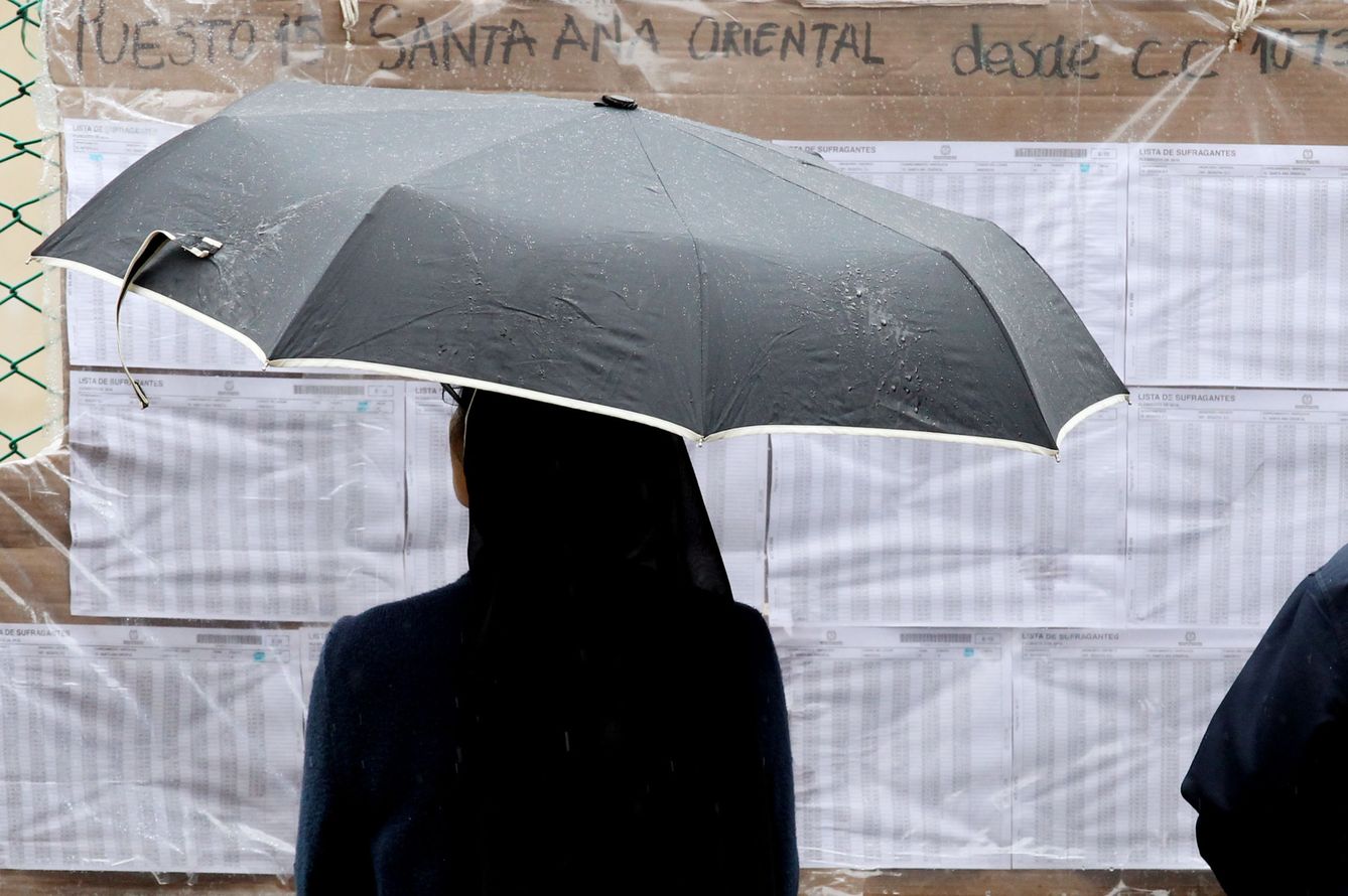 Una monja se resguarda de la lluvia mientras busca su puesto de votación. (EFE)