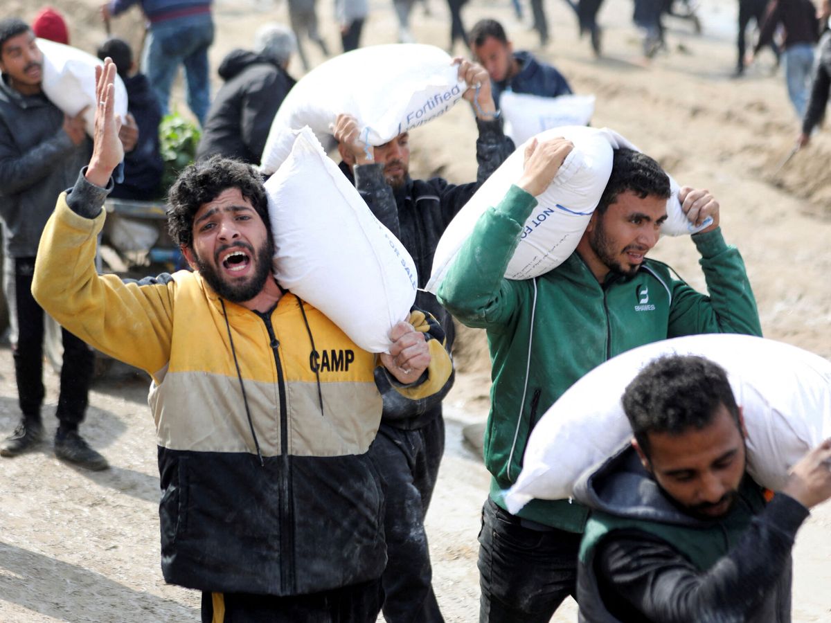 Foto: Palestinos cargan con sacos de harina distribuidos por un camión de ayuda humanitaria en la Ciudad de Gaza. (Reuters/Kosay Al Nemer)
