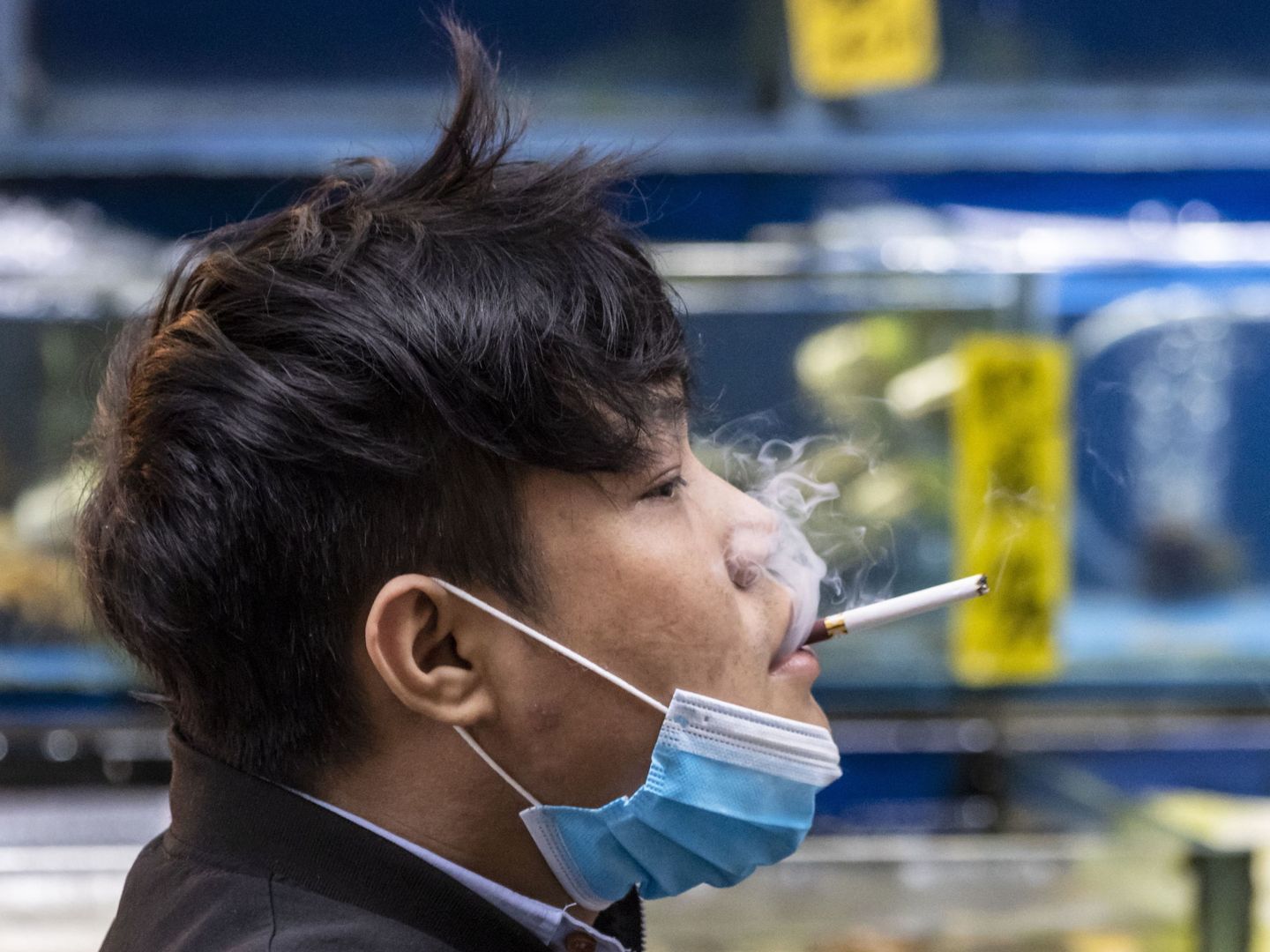 Un hombre se quita la mascarilla para echarse un cigarrillo en Guangzhou (EFE / EPA)