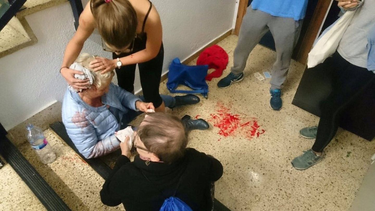 Una mujer atiende a la anciana herida tras una intervención policial en un colegio de Barcelona. (Reuters)