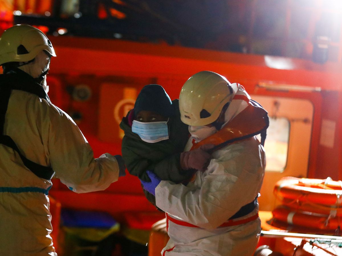 Foto: Dos rescatadores desembarcan a un menor inmigrante en el puerto de Arguineguín (Gran Canaria), el pasado 15 de enero. (Reuters)