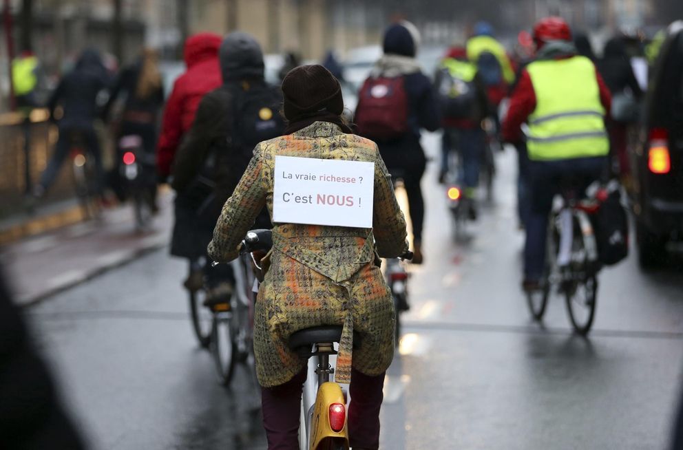 Una ciclista con una señal que reza '¿Verdadera riqueza? Esto somos', en una huelga en Bruselas (Reuters).