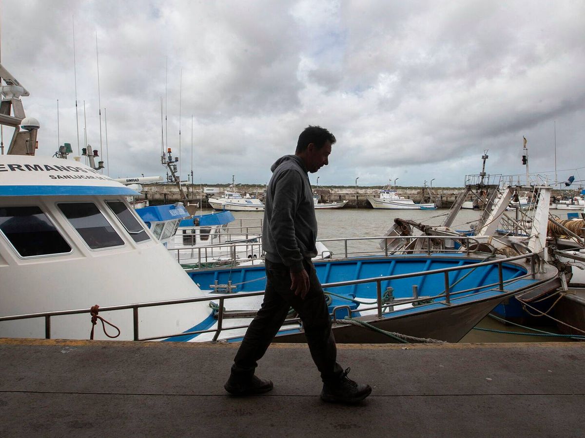 Foto: Un hombre pasa por delante de la flota pesquera de Sanlúcar, atracada el pasado marzo en protesta por la subida de combustibles. (EFE/Román Ríos)
