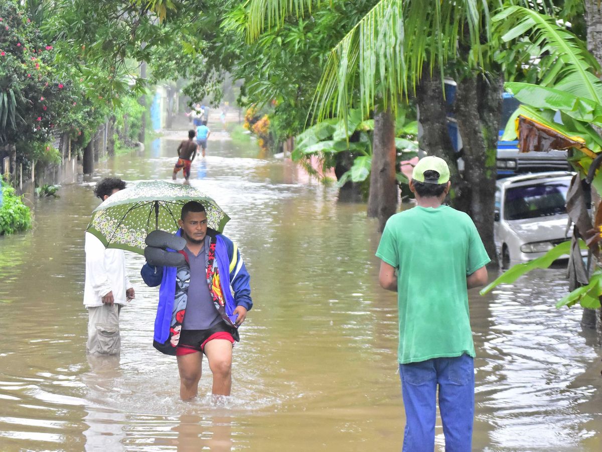 Foto: Un hombre camina por una calle inundada hoy en La Lima. (EFE)