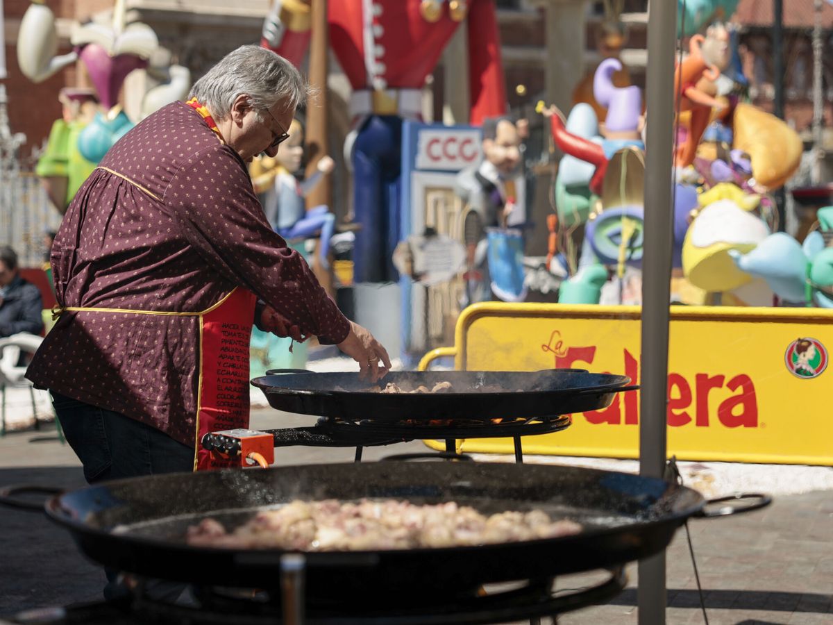 Foto: Una persona perteneciente a un casal fallero, cocina una paella en la calle, en las fallas de Valencia. (EFE/Biel Aliño)