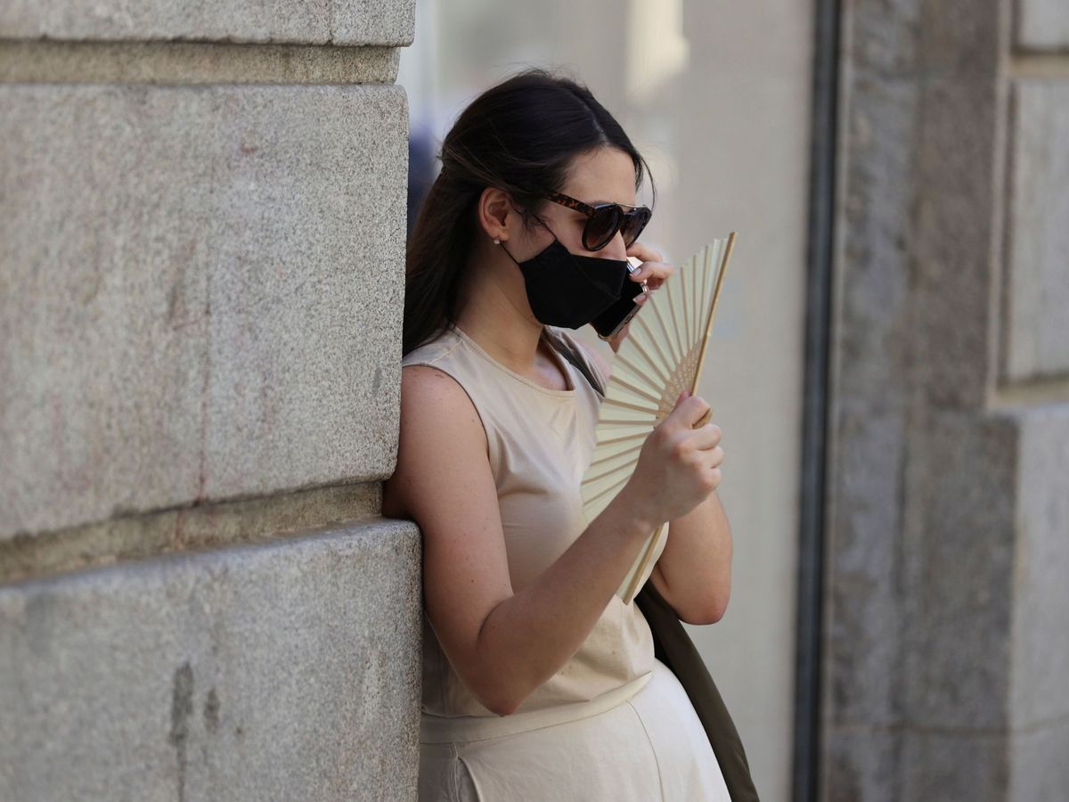 Foto: Una mujer con mascarilla y abanico por las calles de Madrid. (EFE)