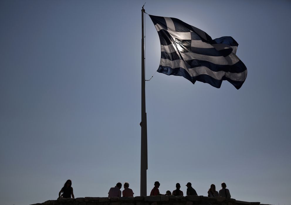 Foto: Un grupo de turistas bajo la bandera griega en lo alto de la colina de la Acrópolis, en Atenas, en julio de 2013 (Reuters). 