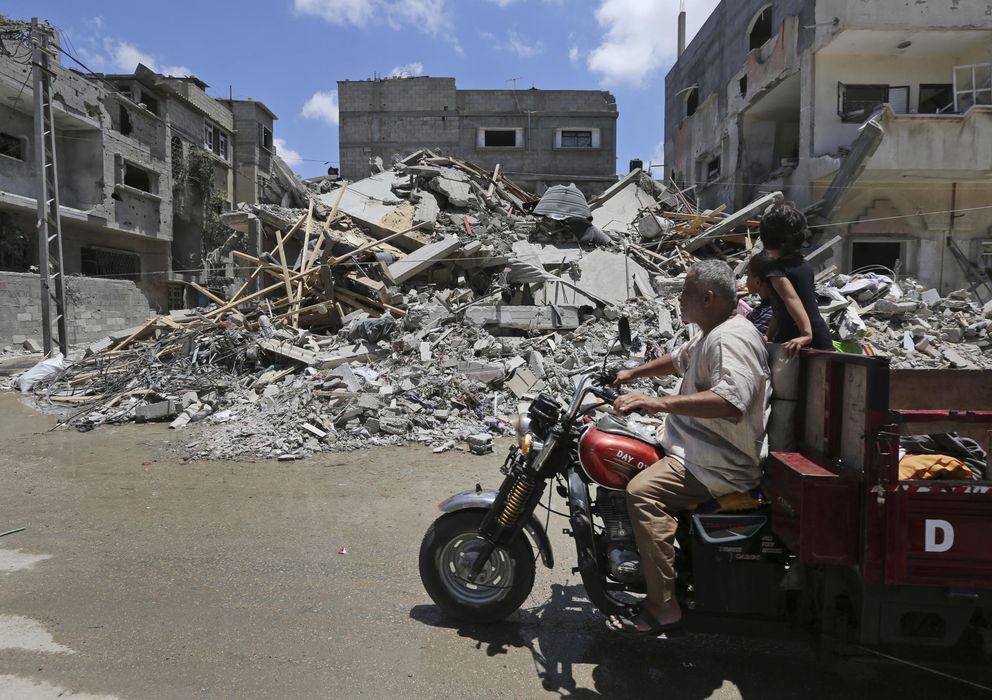 Foto: Palestinos conducen entre escombros de edificios atacados por la aviación israelí en Rafah, al sur de la Franja (AP).
