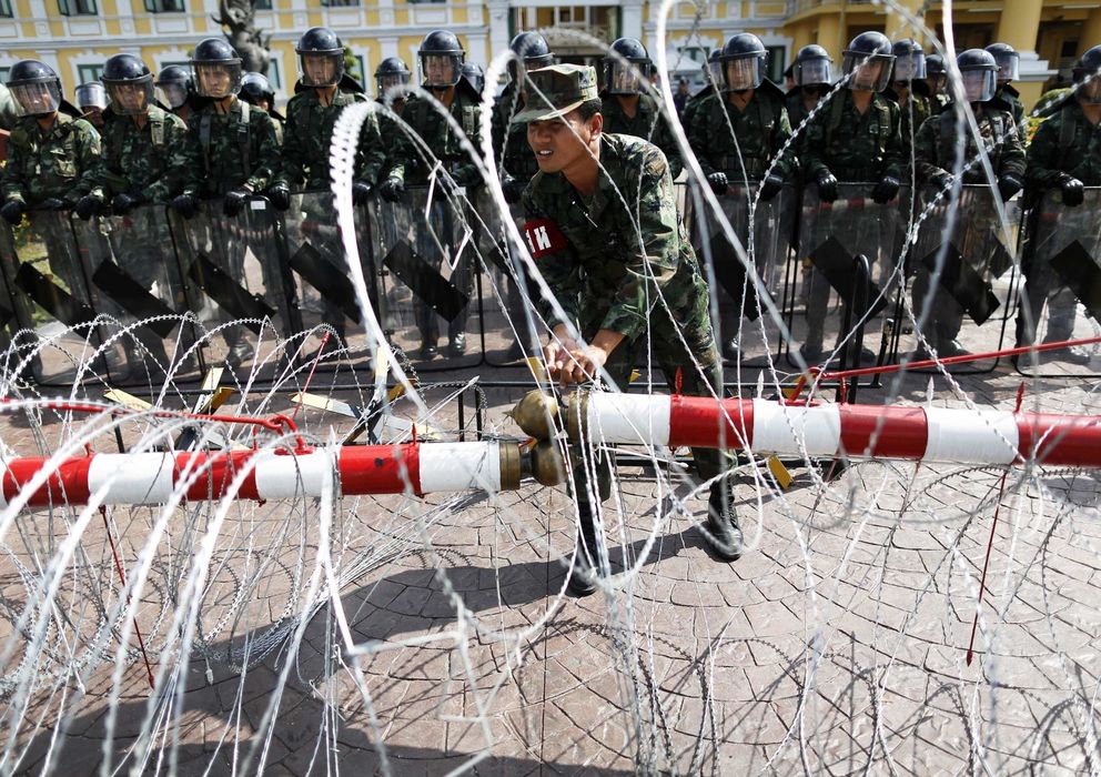 Foto: Un oficial ajusta la alambrada colocada para contener las protestas antigubernamentales ante el Ministerio de Defensa en Bangkok. (Reuters)