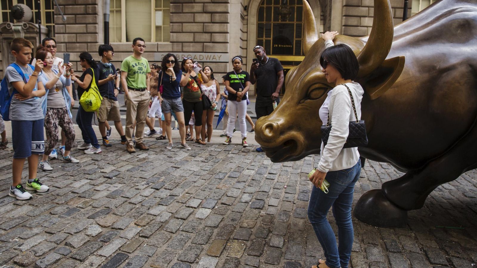 Foto: Turistas se fotografían junto a la estatua del toro de Wall Street, que representa la subida en la bolsa. (Reuters)