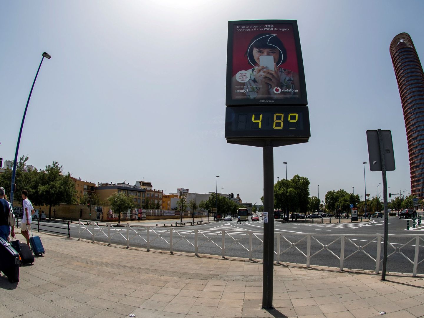 Turistas pasan junto a un termómetro de Sevilla que marca 48ºC. (EFE)