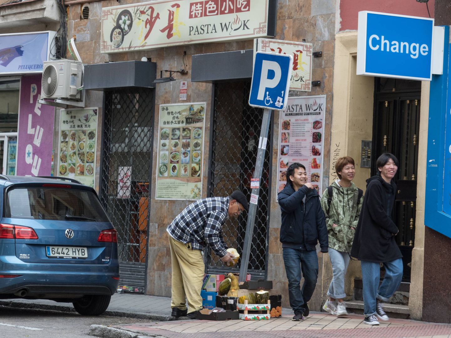 Tres jóvenes pasan de largo por un restaurante cerrado en Usera, Madrid. (D. B.)