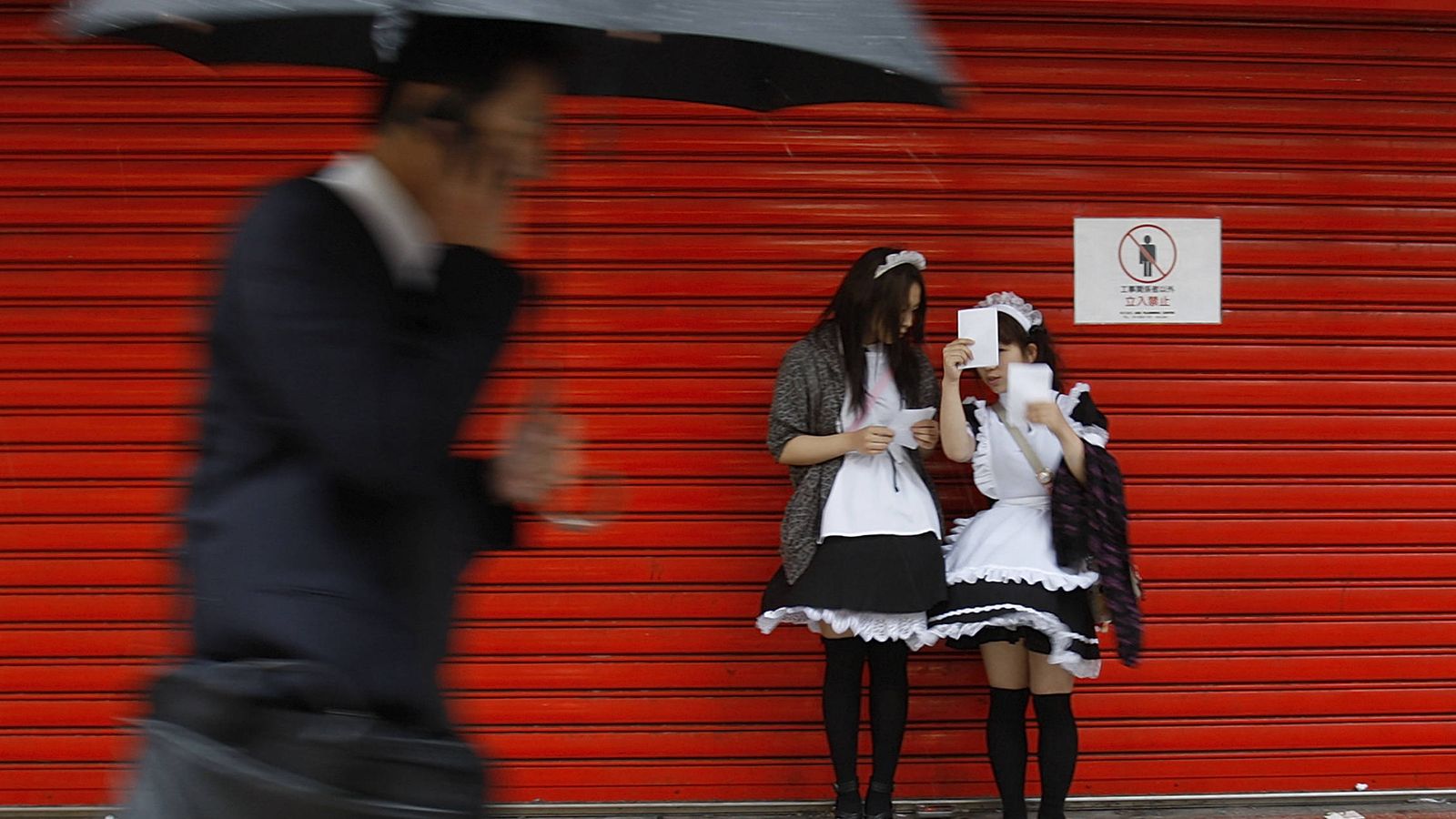 Foto: Un hombre pasa ante dos jóvenes japonesas disfrazadas en el centro de Tokio (Reuters).