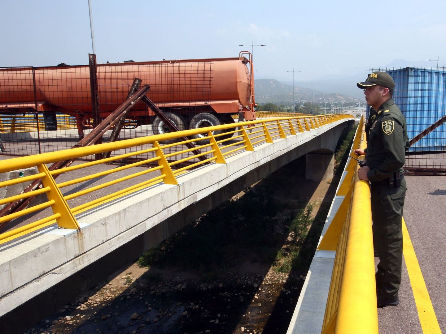 Un policía colombiano frente a los contenedores que bloquean el paso en el puente de Tienditas, en la frontera con Venezuela, el 6 de febrero de 2019. (Reuters)