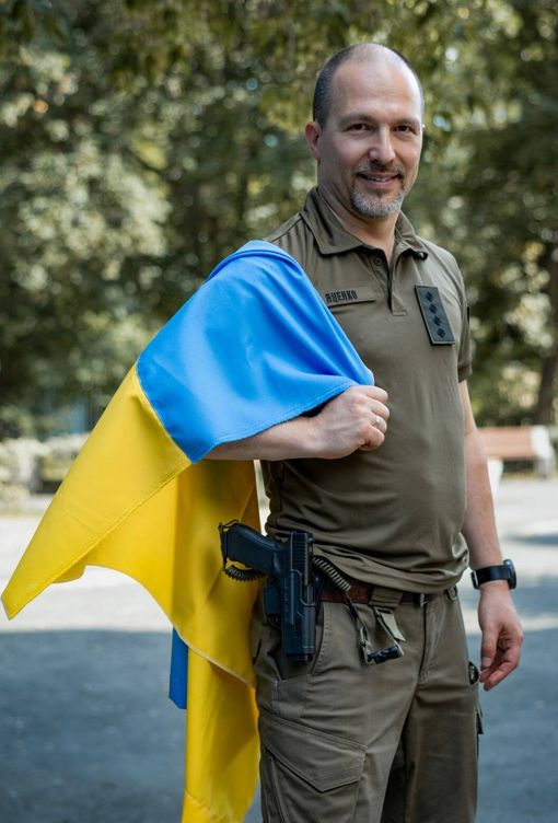 El escritor ucraniano Petro Yatsenko, en su uniforme militar y con una bandera de Ucrania. 