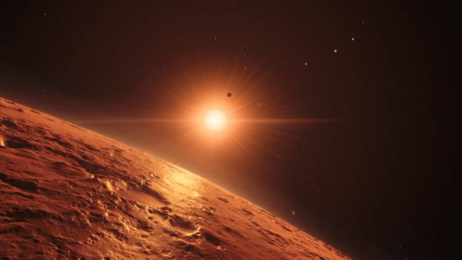 Foto: Representación artística de la superficie de uno de los planetas del nuevo sistema con la estrella TRAPPIST-1 brillando al fondo