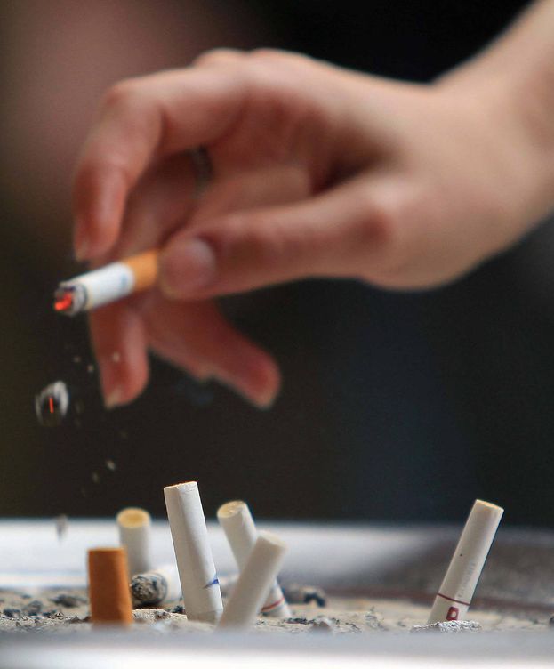 Foto: Una persona bota ceniza junto a colillas de cigarrillos. (Efe)