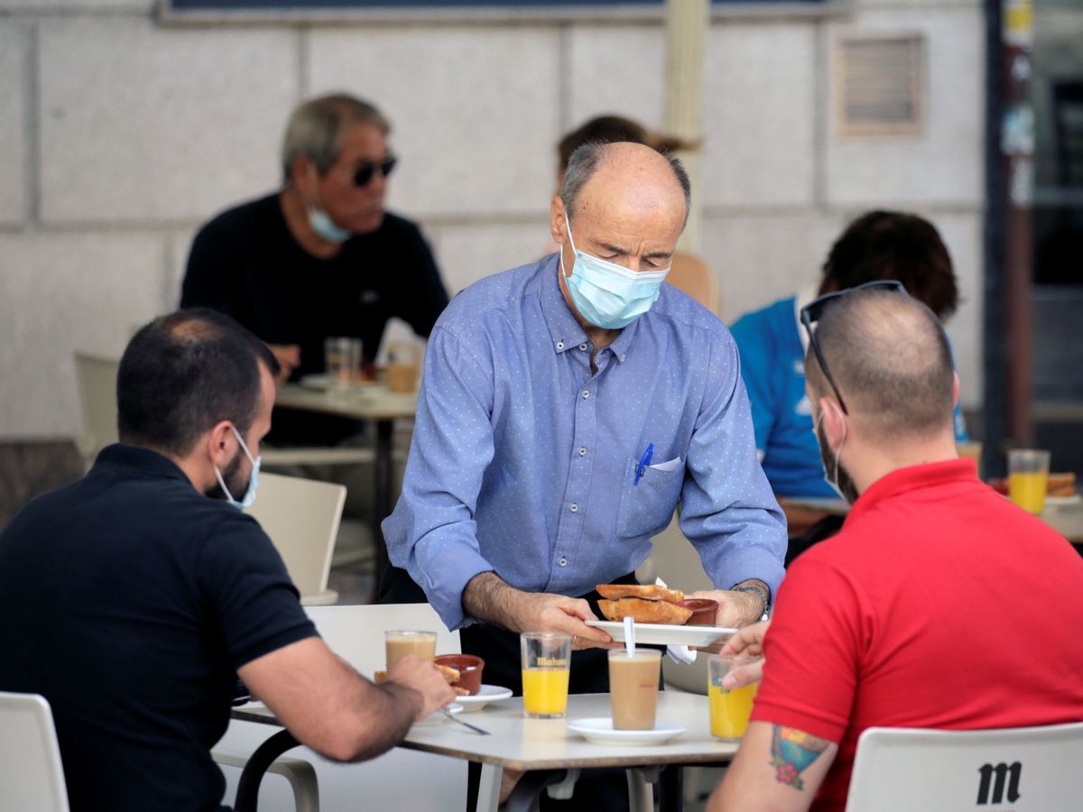 Foto: Un camarero con mascarilla atiende en una terraza de Madrid. (Reuters)