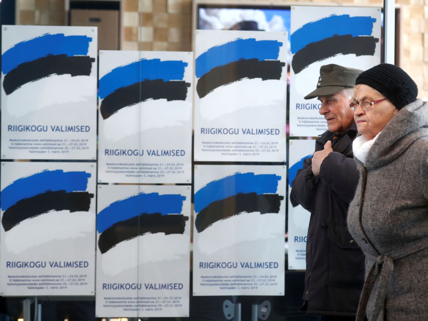 Dos personas pasan frente a unos carteles electorales en Parnu, Estonia, el 3 de marzo de 2019. (Reuters)