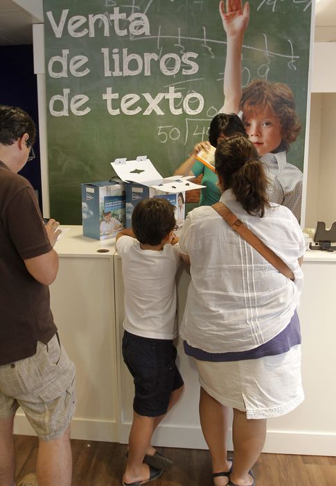 Foto: Una mujer espera ante el mostrador de una gran superficie de Madrid para hacerse con los libros de texto de su hijo. (EFE)