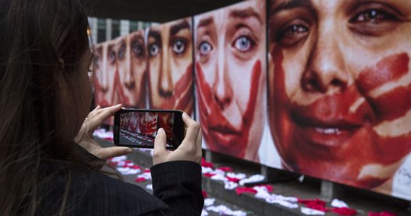 Foto: Una mujer toma fotos a una instalación con imágenes de modelos que representan a mujeres que sufrieron algún tipo de abuso sexual. (EFE) 