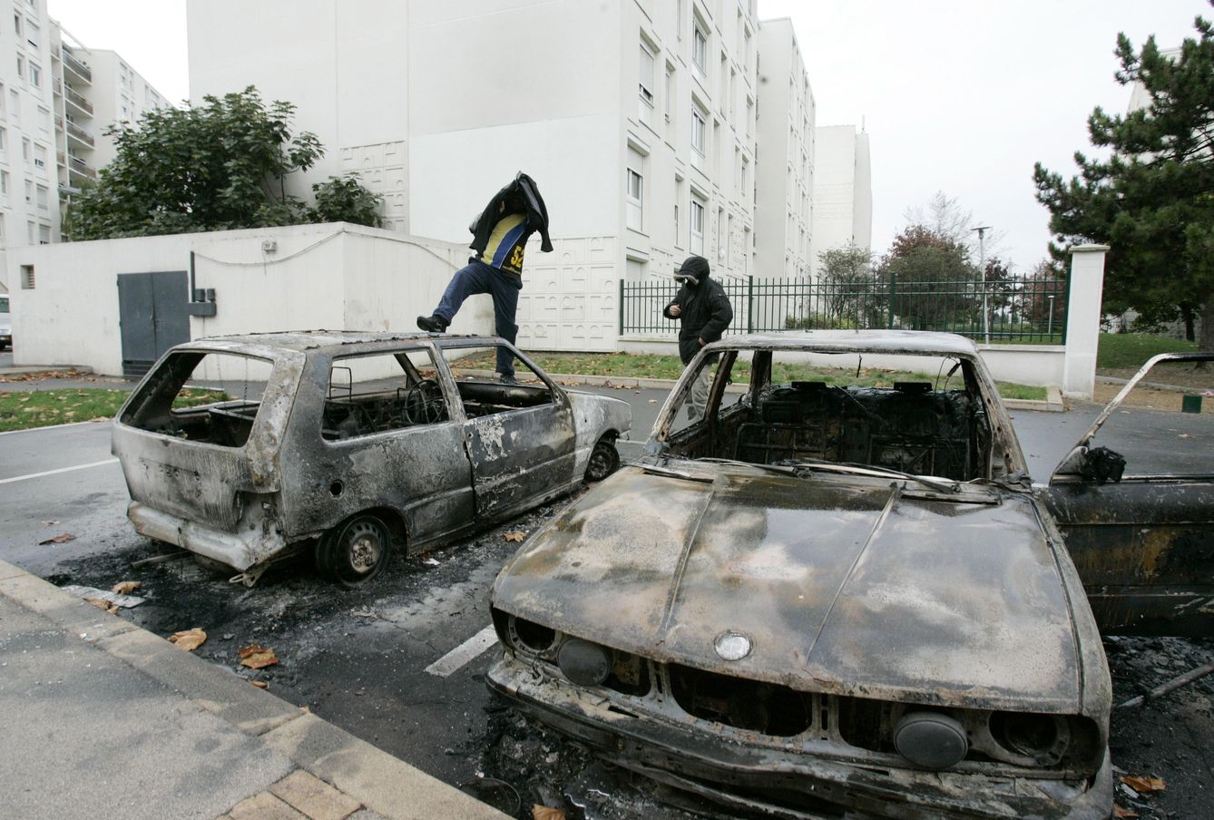 Jóvenes caminan sobre vehículos quemados en el suburbio parisino de Sevran, en noviembre de 2005. (Reuters)