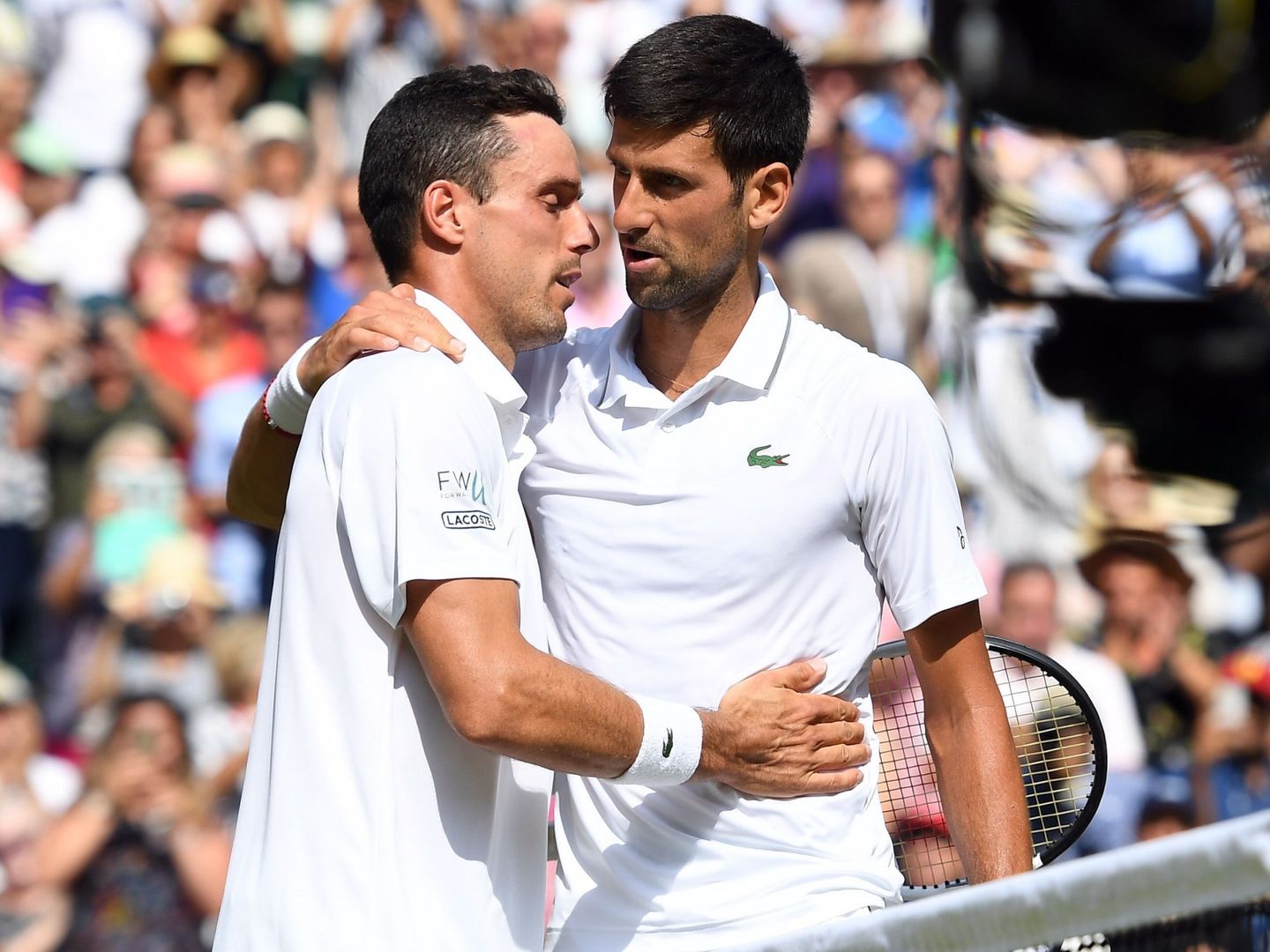 Bautista y Djokovic se saludan en la red tras las seminfinales de Wimbledon. (EFE)