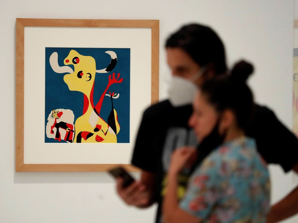 Foto: Una pareja frente a la obra 'Mujer y perro delante de la luna' de Joan Miró en el museo Reina Sofía tras su reapertura. (EFE)