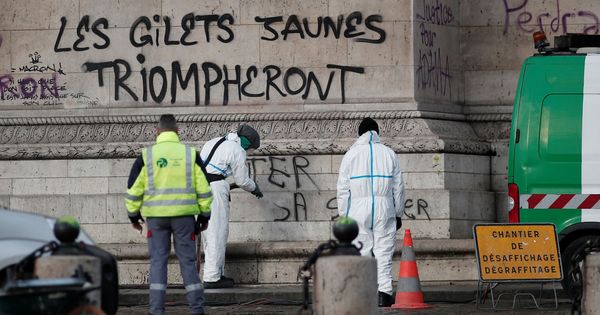 Foto: Operarios de limpieza se ocupan del Arco del Triunfo bajo una pintada que dice "los chalecos amarillos triunfarán". (Reuters)