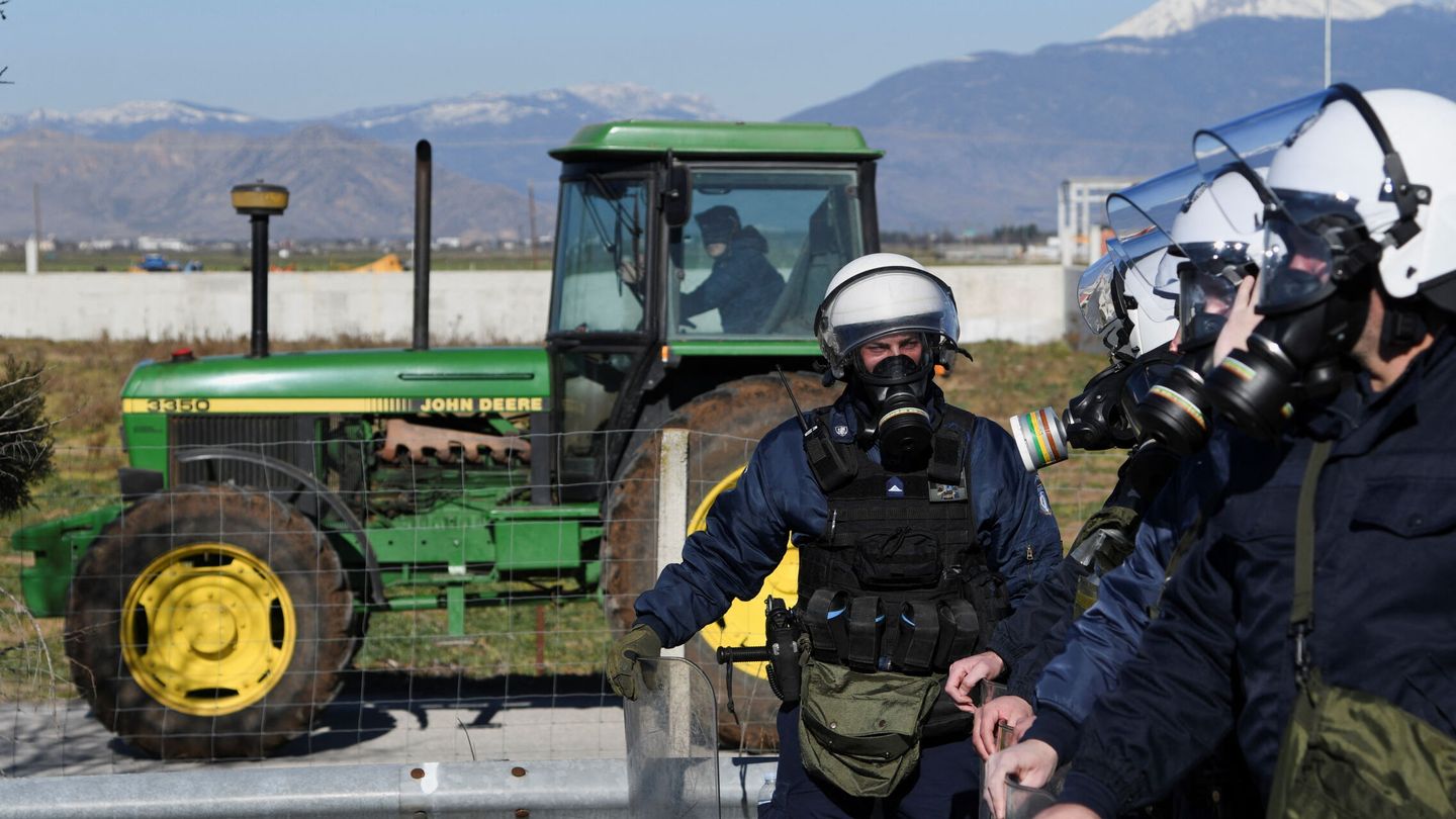 Varios antidisturbios junto a un tractor. (EFE)