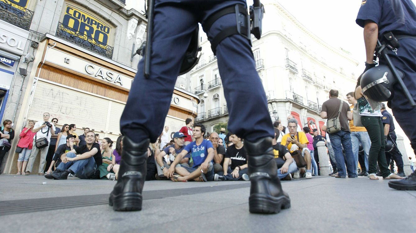 Foto: Centenares de personas se concentran en las inmediaciones de la Puerta del Sol custodiada por la policía. EFE