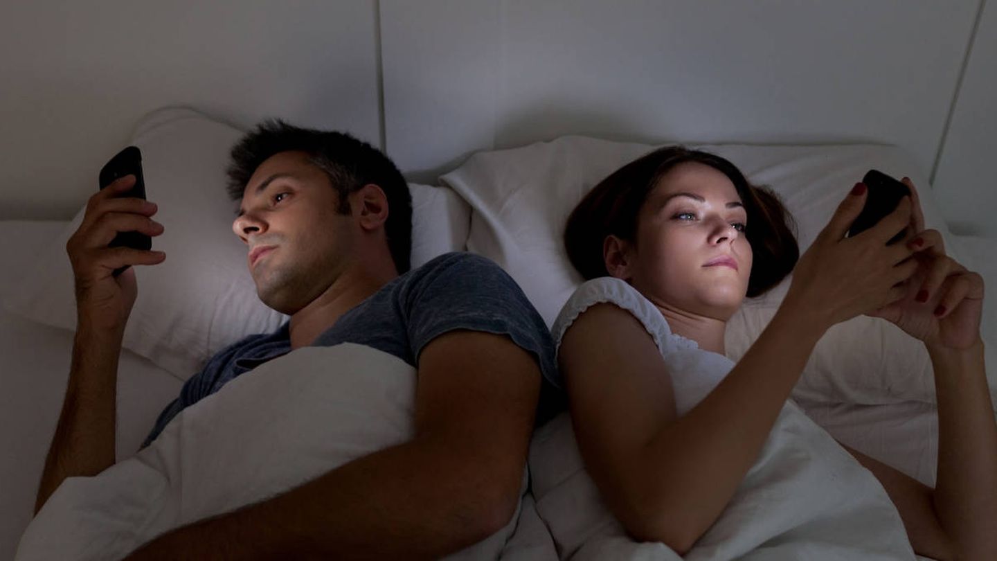 Young couple with smartphones in their bed
