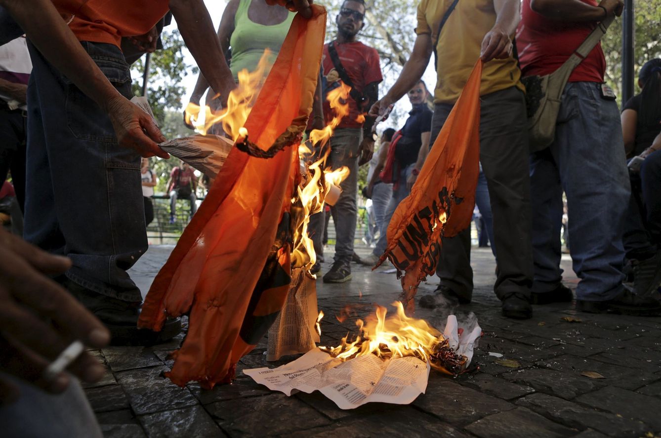 Seguidores del presidente Maduro en Caracas queman una bandera de la opositora Mesa de Unidad Nacional. (Reuters)
