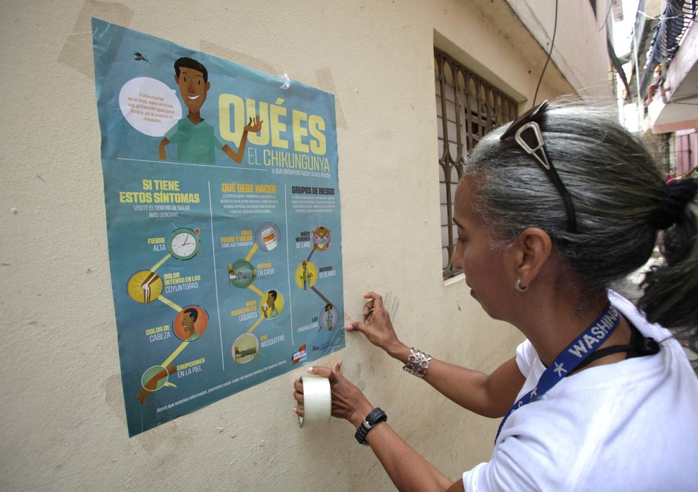 Foto: Una voluntaria coloca un cartel de alerta en Santo Domingo. (Efe)