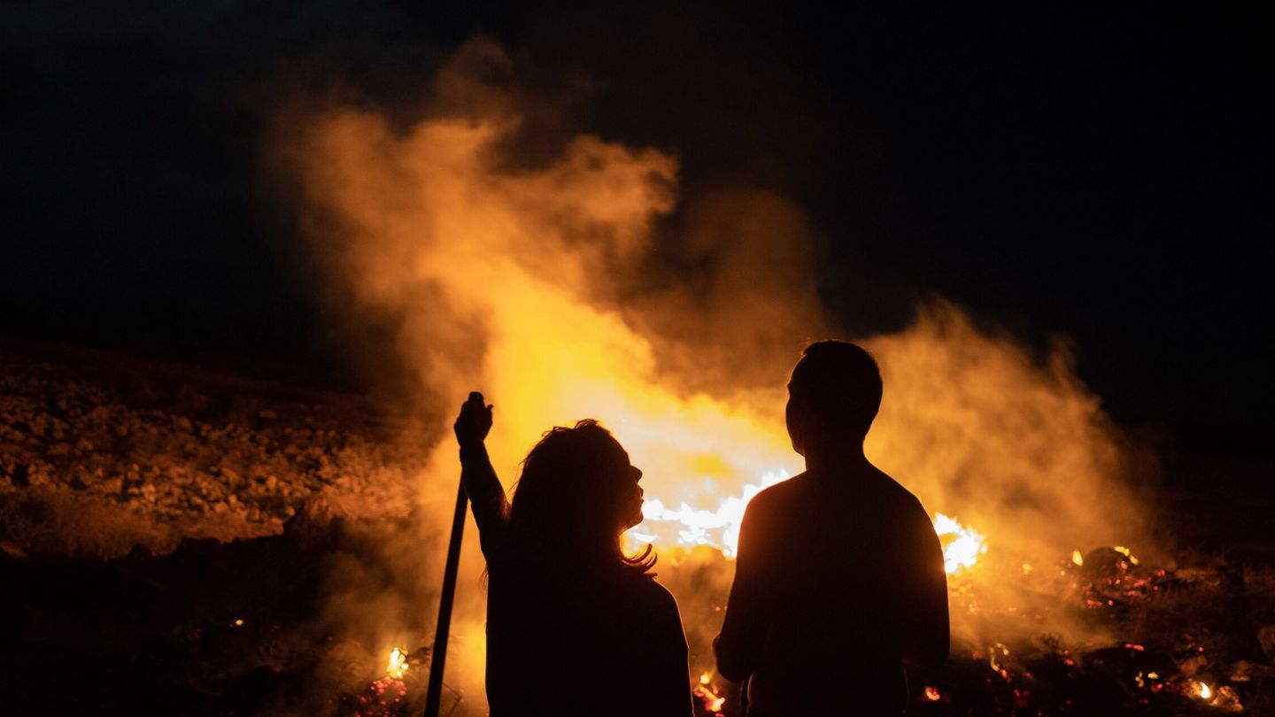 Varios jóvenes celebran la noche de San Juan junto a una hoguera en las inmediaciones de la localidad de Lajares, en La Oliva (Fuerteventura). (EFE/Carlos de Saá)