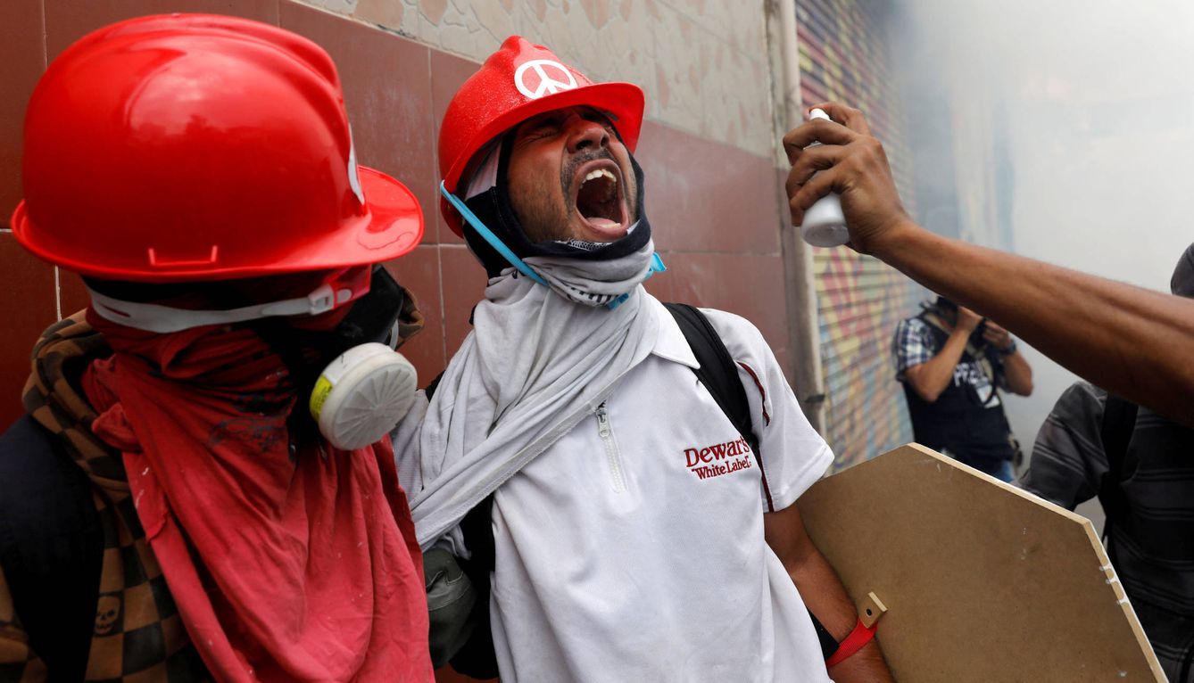 Manifestantes opositores afectados por el gas lacrimógeno durante protestas en Caracas. (Reuters)