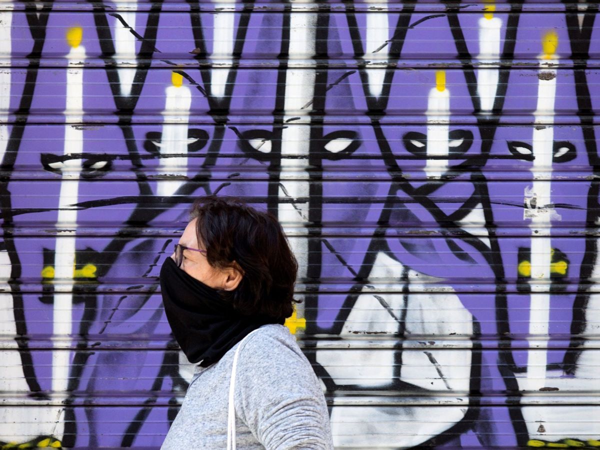 Foto: Una mujer camina delante de un mural sobre la Semana Santa e Málaga (EFE)