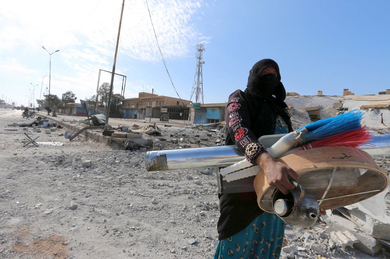 Una mujer carga con bienes tras un saqueo en Al-Shadadi, en Siria, en febrero de 2016 (Reuters).