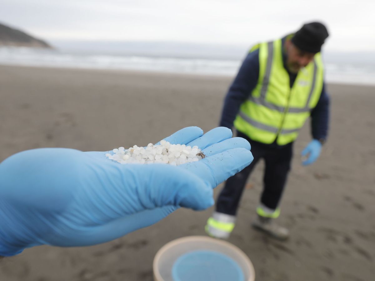 Foto: Un operario recoge 'pellets' de plástico en la playa de Otur, en Valdés (Asturias). (EP/Jorge Peteiro)