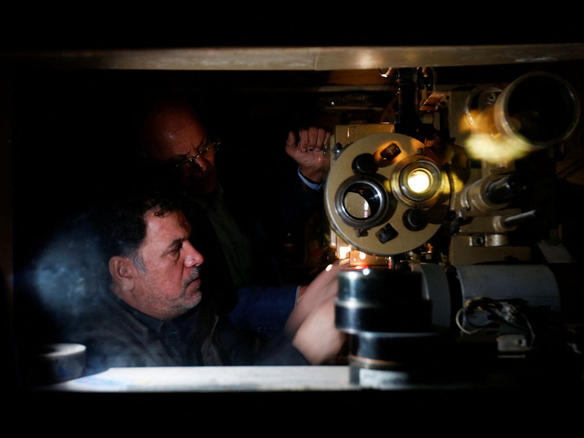 Foto: Dos aficionados al cine manejan un proyector. (Reuters)