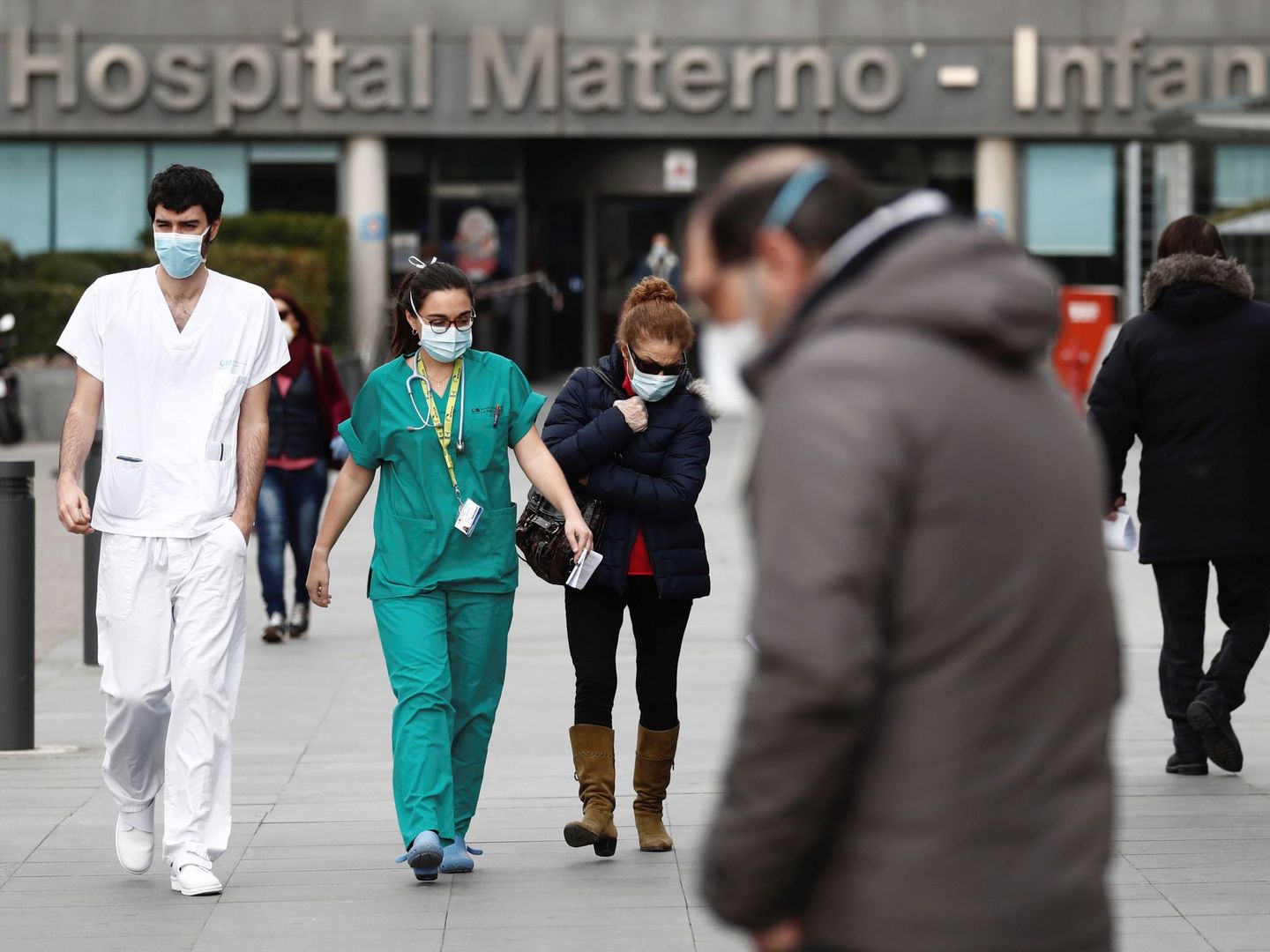 Trabajadores de la sanidad con mascarillas caminan junto a la entrada del hospital La Paz de Madrid. (EFE)