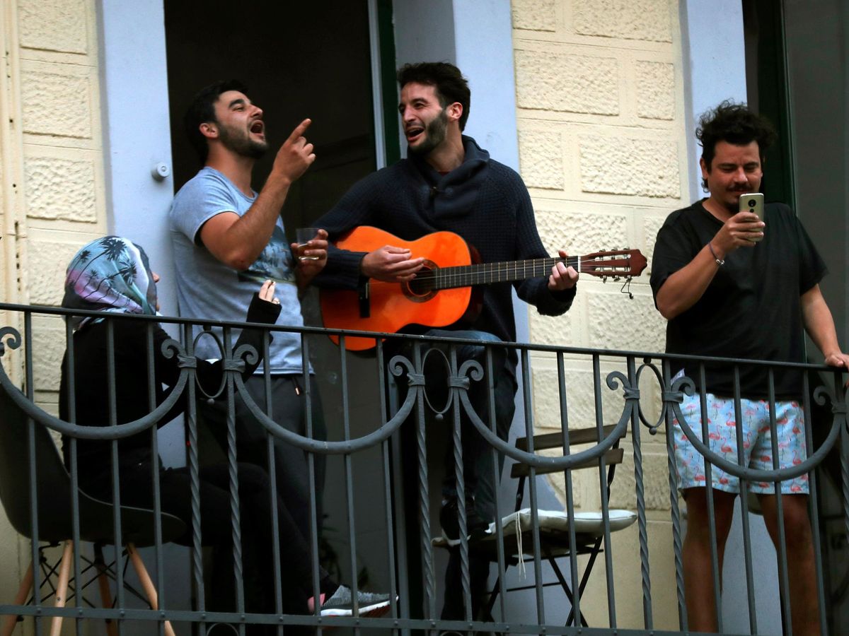 Foto: Vecinos de L'Hospitalet salen a sus balcones como cada día a animar y homenajear a los sanitarios. (EFE)