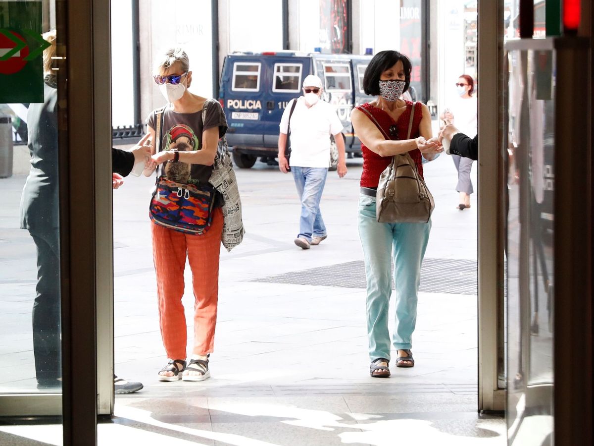 Foto:  Dos mujeres desinfectan sus manos antes de acceder a un centro comercial de la madrileña calle Preciados. (EFE) 