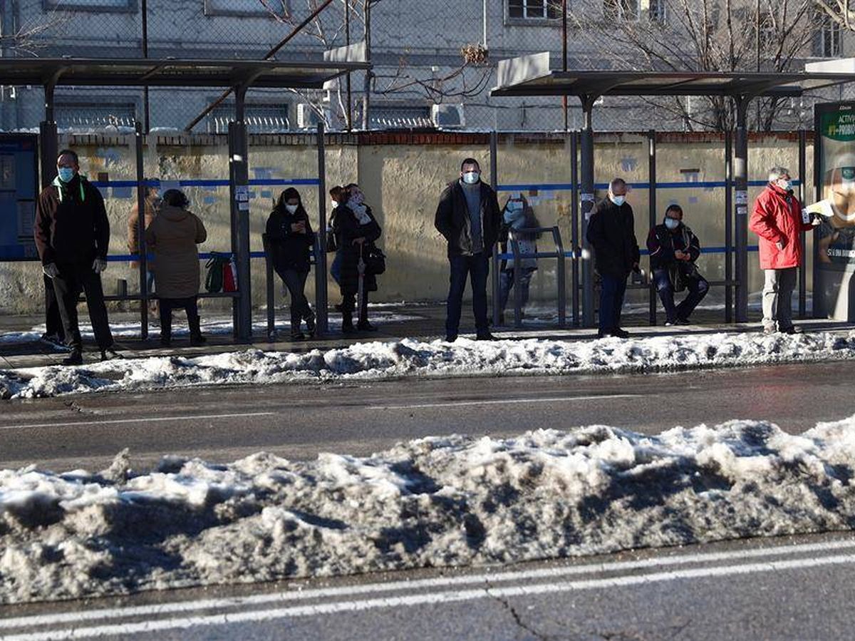Foto: Varias personas esperan en una parada de autobús tras retirarse la nieve (EFE)